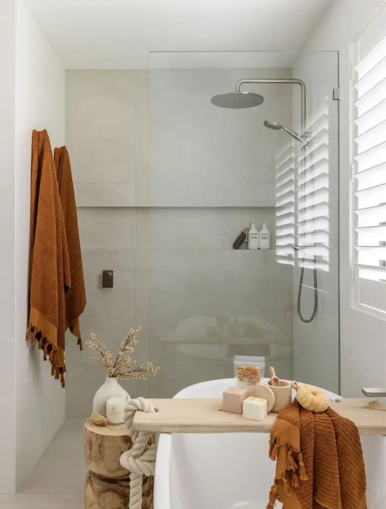 Walk-in shower with brushed-nickel rain shower beside a freestanding bath and timber bath caddy