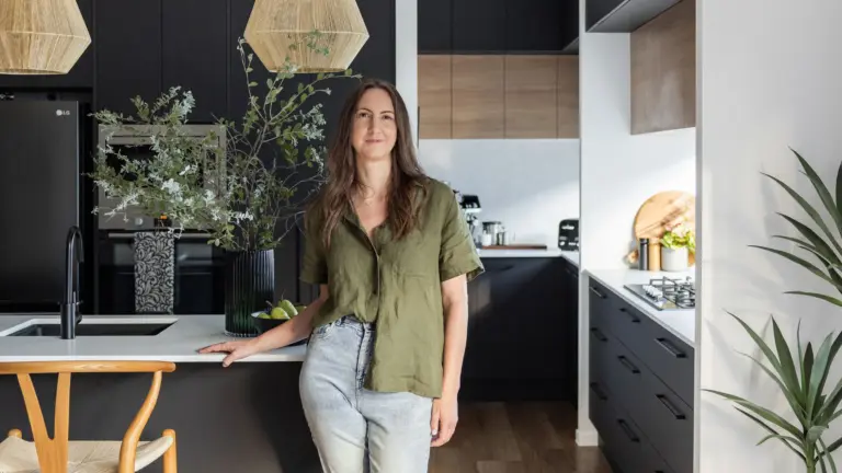 Interior designer Julia Lloyd in a black and timber kitchen with rattan pendants