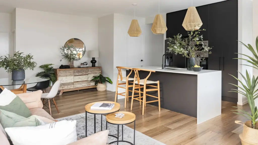Open-plan kitchen and living area with a dark island bench and woven pendant lights