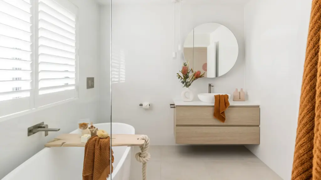 Award-winning small bathroom with a wall-hung timber vanity, round mirror and freestanding bath
